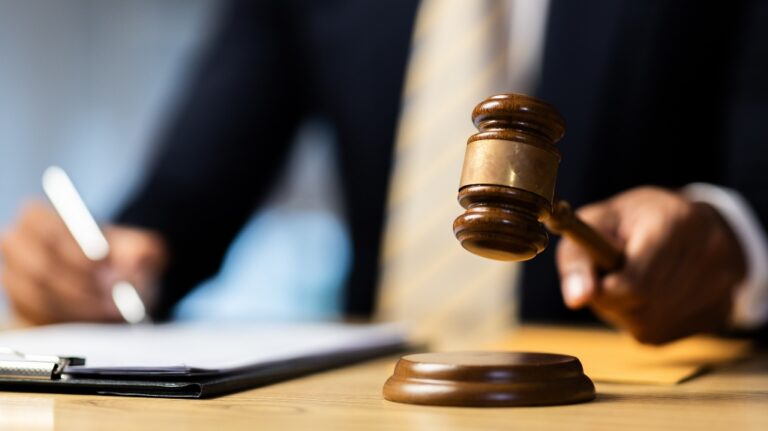 Male lawyer working at the desk in the office holding the gavel